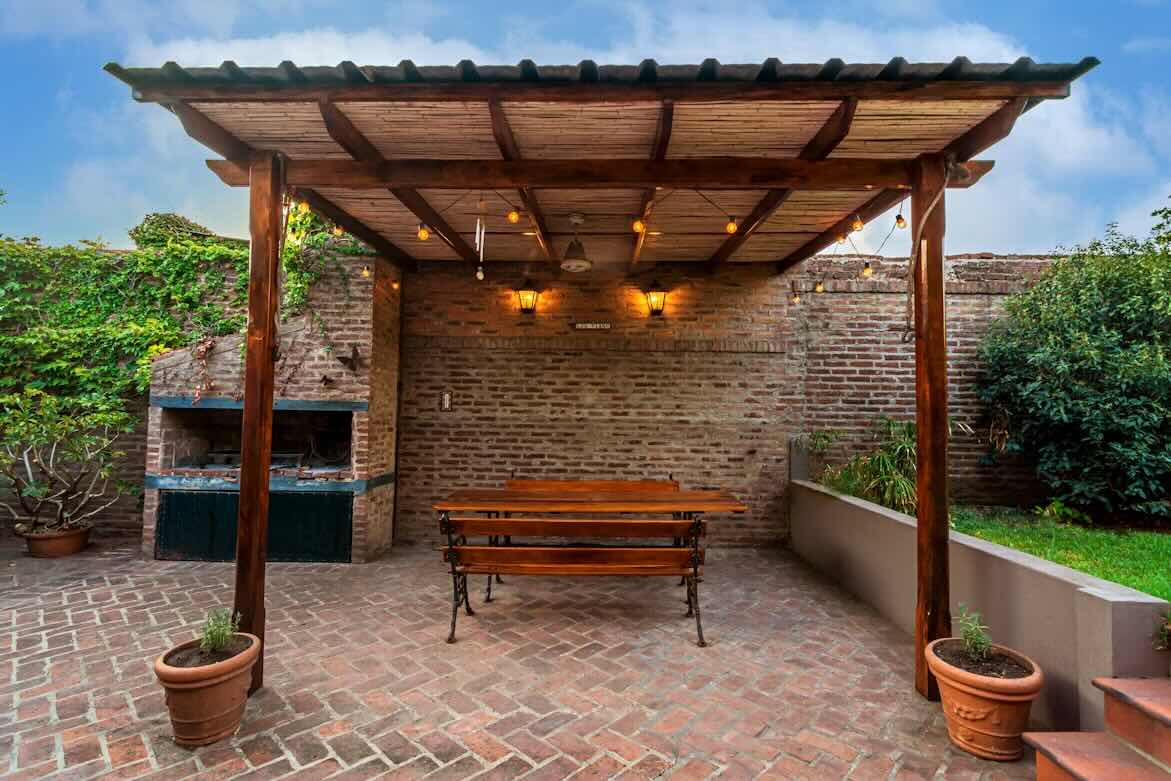 A backyard patio with a brick paved ground, and brick accent wall and pizza oven