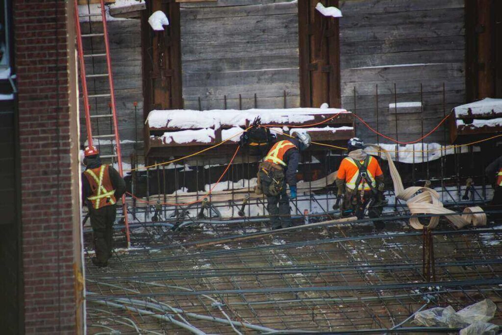 Workers at a construction site with stone laying on various beams and equipment