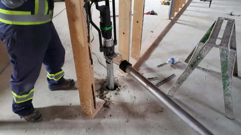 Close up of a ground screw driver drilling on concrete