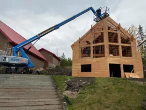 Rentco boom lift reaching over a timber frame building under construction